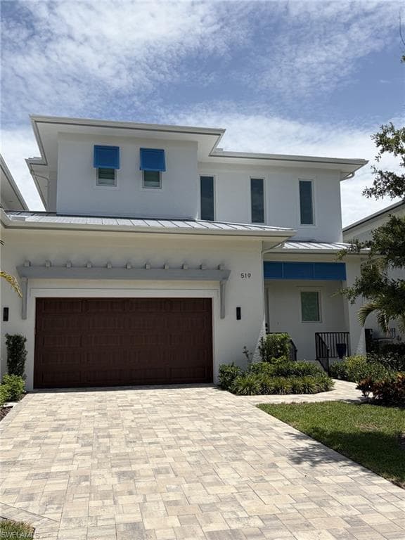 Modern two-story residence featuring a white stucco exterior and a metal roof