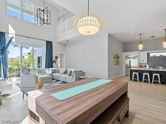 Open-concept living space featuring wood-finish flooring, a two-story ceiling, and a kitchen with an island