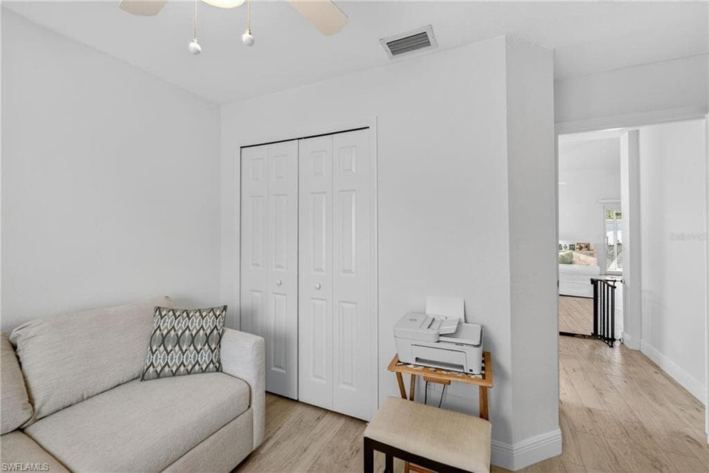 White interior walls featuring a ceiling fan with integrated lighting, bi-fold closet doors, and wood-finish flooring