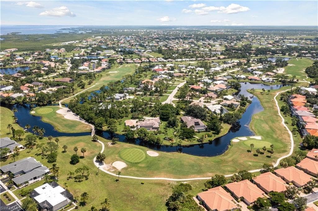 Expansive aerial perspective showcasing a residential community with a prominent golf course and waterways