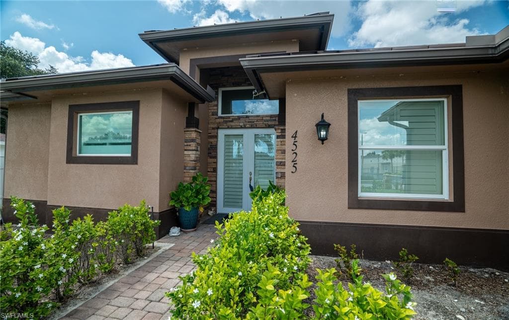 Contemporary exterior featuring a stucco finish with contrasting trim and a stone veneer accent