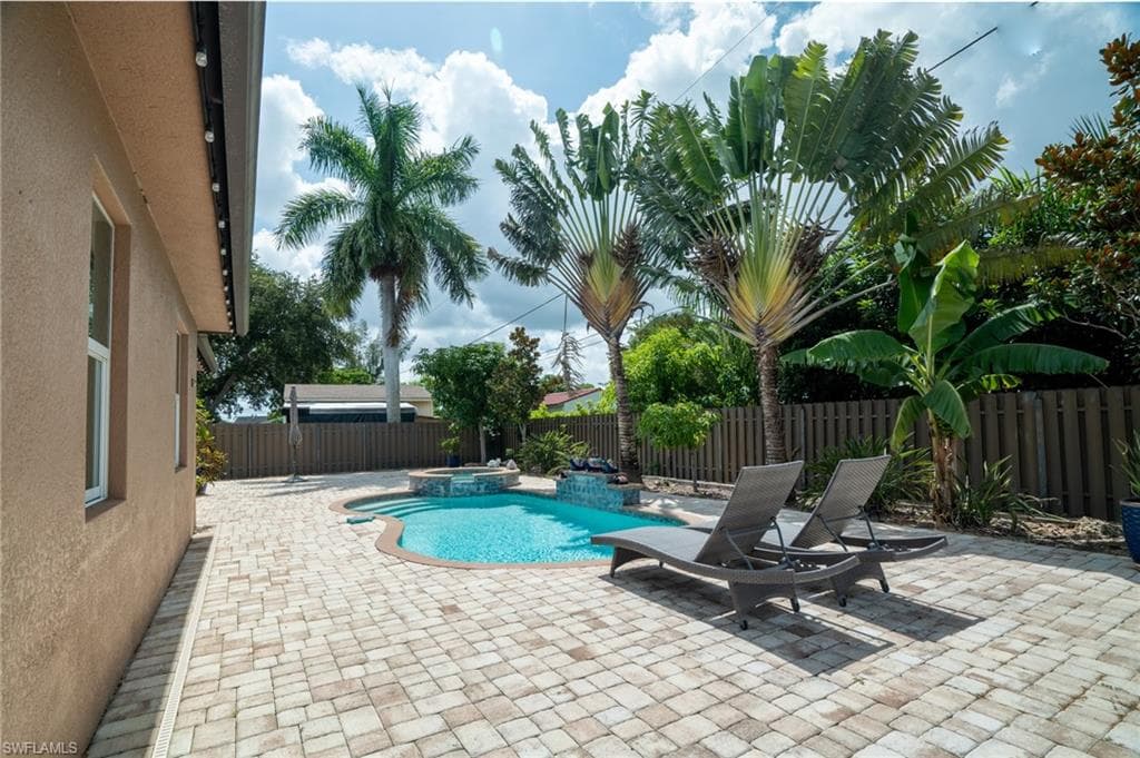 Expansive paver patio featuring a freeform swimming pool with an attached spa