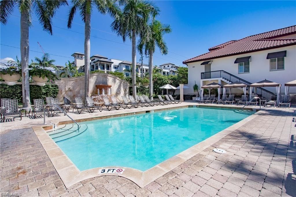 Expansive outdoor pool area featuring a rectangular pool with integrated steps, surrounded by paver decking