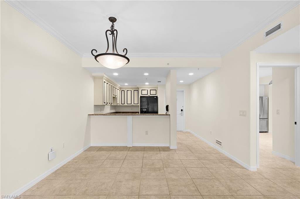Open concept living space with light neutral walls, crown molding, and tiled flooring
