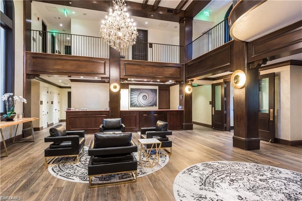 Two-story foyer featuring wood-finish flooring, a grand chandelier, and dark wood beams