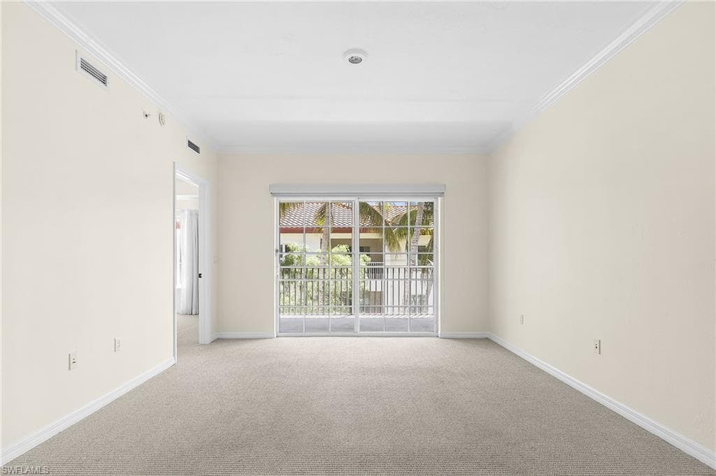 Living area featuring neutral wall tones, crown molding, light gray carpeting, and a sliding glass door leading to a private balcony