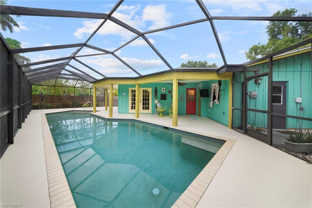 Screened-in swimming pool featuring a light-colored deck surround, integrated steps, and handrails