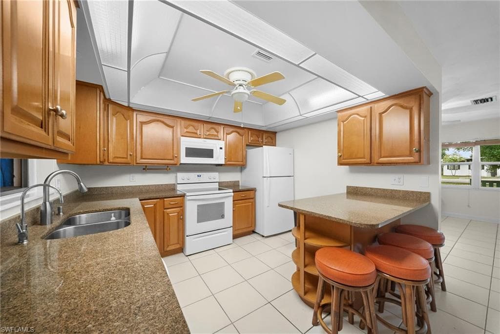 Kitchen featuring wood cabinetry, granite-style countertops, and white appliances