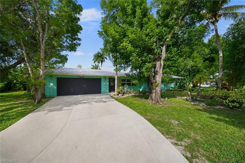 Exterior featuring a vibrant turquoise facade, a black garage door, and a light-colored asphalt shingle roof
