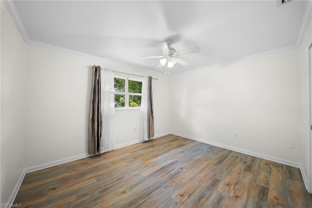 Room featuring wood-finish flooring, white walls, and a window with natural light
