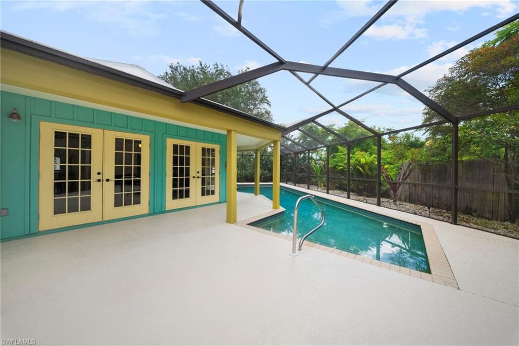 Enclosed swimming pool with a screen enclosure, ample patio decking, and direct access through multiple sets of French doors