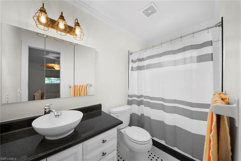 Bathroom featuring a white vessel sink, black countertop, and white cabinetry
