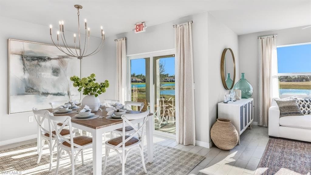 Model home. Dining room with light wood-style floors, a chandelier, and a water view