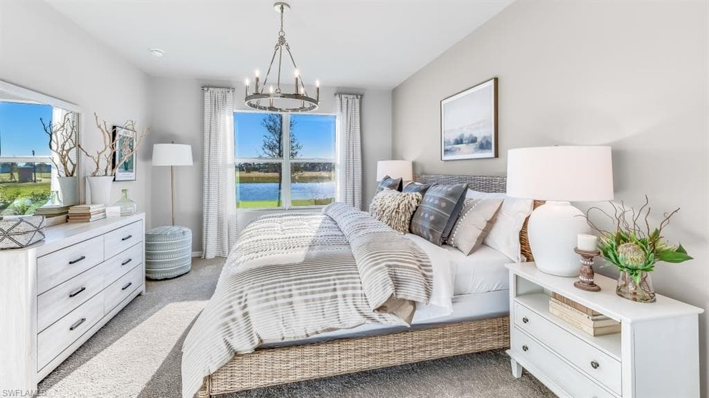 Model home. Bedroom featuring light colored carpet, a water view, and hanging lights