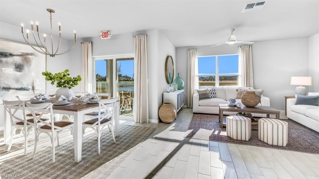 Model home. Living area featuring ceiling fan, wood tiled floors, hanging lights, and a water view