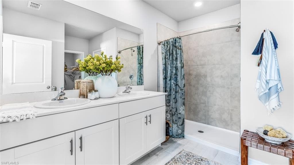 Model home. Bathroom featuring double vanity and a stall shower