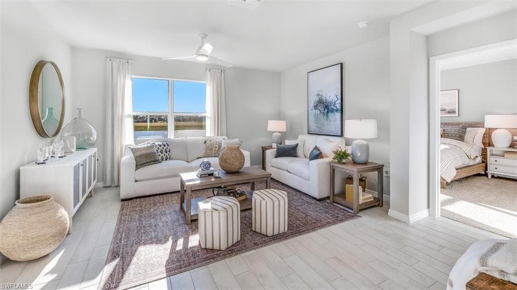 Model home. Living area with light wood-style floors and a ceiling fan
