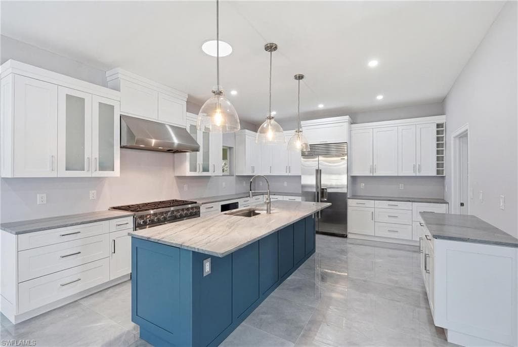 Spacious kitchen featuring an expansive central island with a contrasting blue finish, stone countertop, and integrated sink