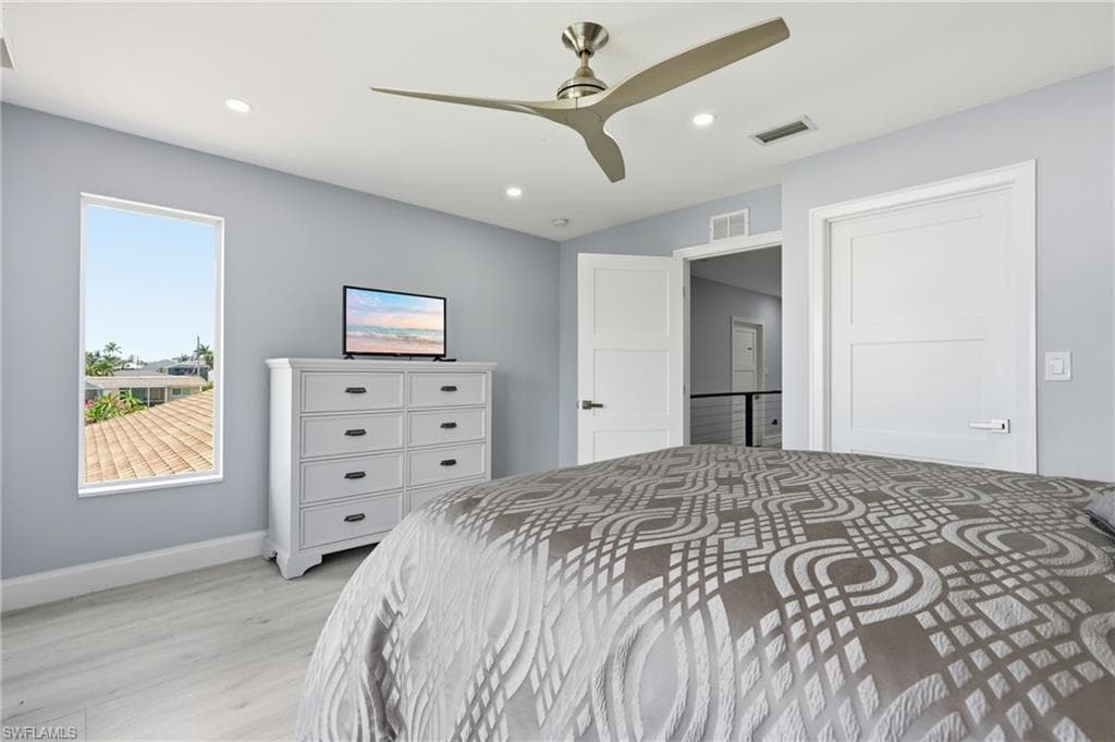 Recessed lighting, a modern ceiling fan, and light wood-finish flooring characterize this room