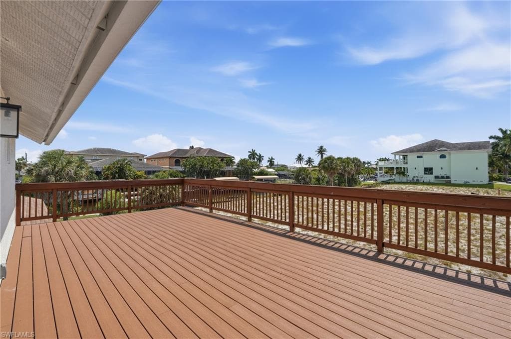 Spacious outdoor deck featuring composite decking, a sturdy wood railing, and a side-mounted exterior light fixture