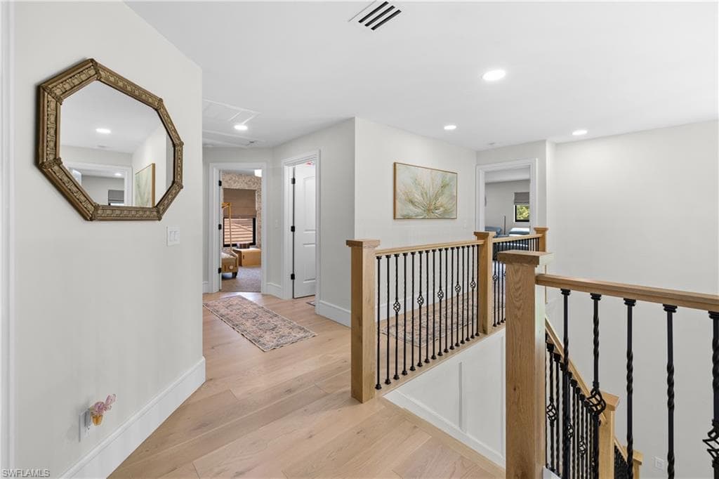 Upper-level hallway featuring light wood-finish flooring, recessed lighting, and white trim