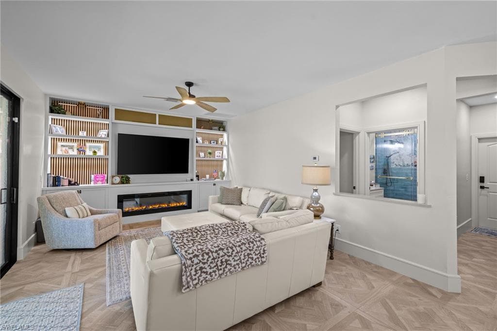 Living area featuring herringbone wood-finish flooring and a built-in media center with shelving