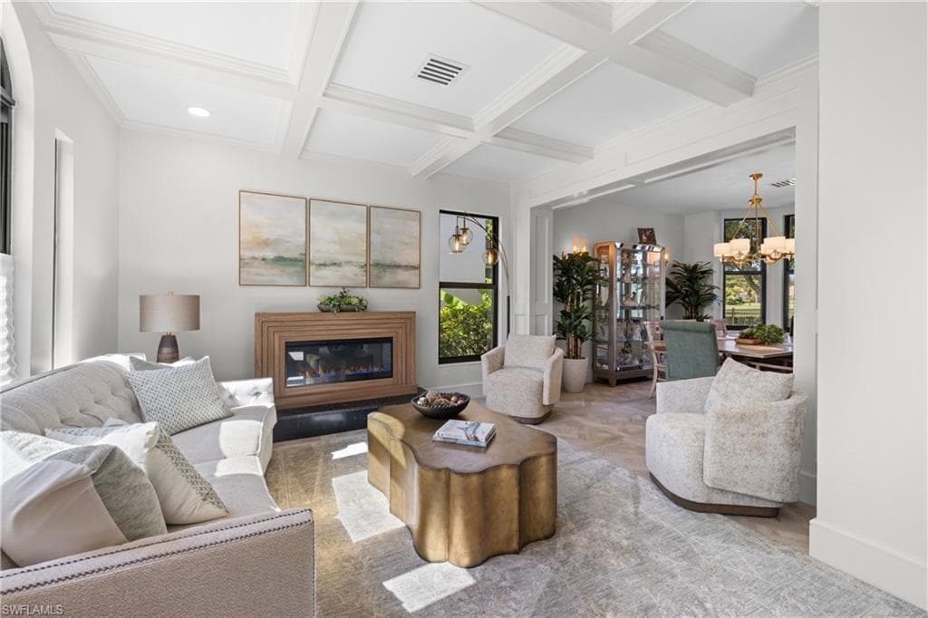 Living area featuring a coffered ceiling, a contemporary fireplace with a wood surround, and light-tone flooring