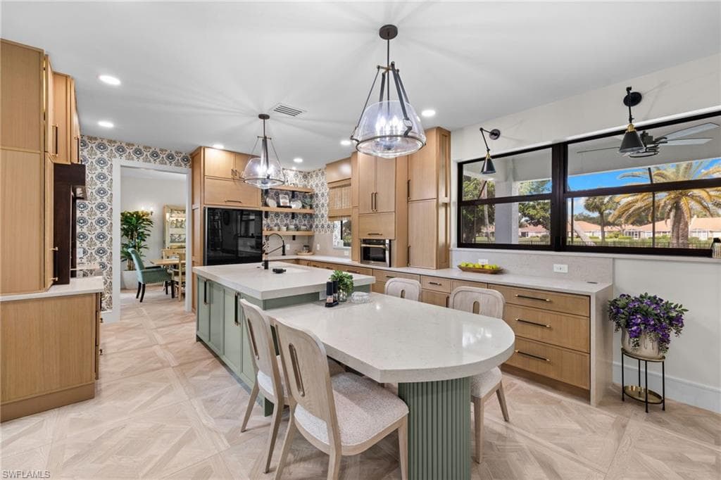 Open-concept kitchen featuring a large central island with an undermount sink, light-toned countertops, and a white range