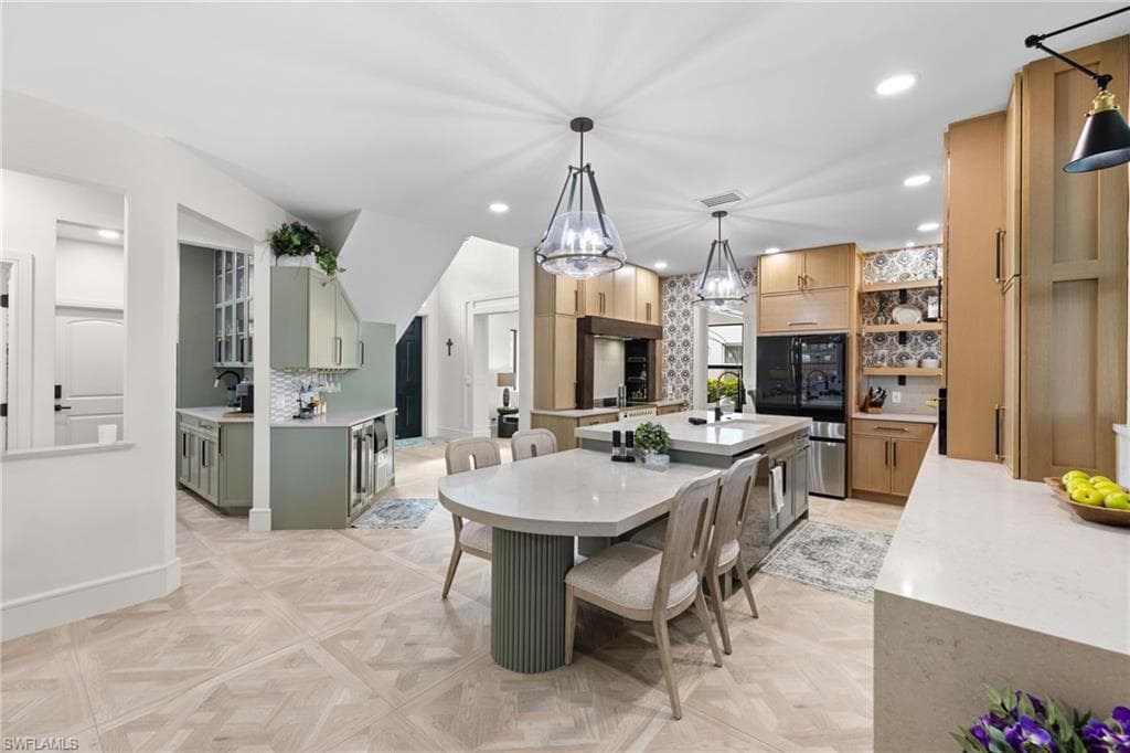 Open concept kitchen featuring wood-finish cabinetry, light-toned countertops, geometric tile flooring, and island seating