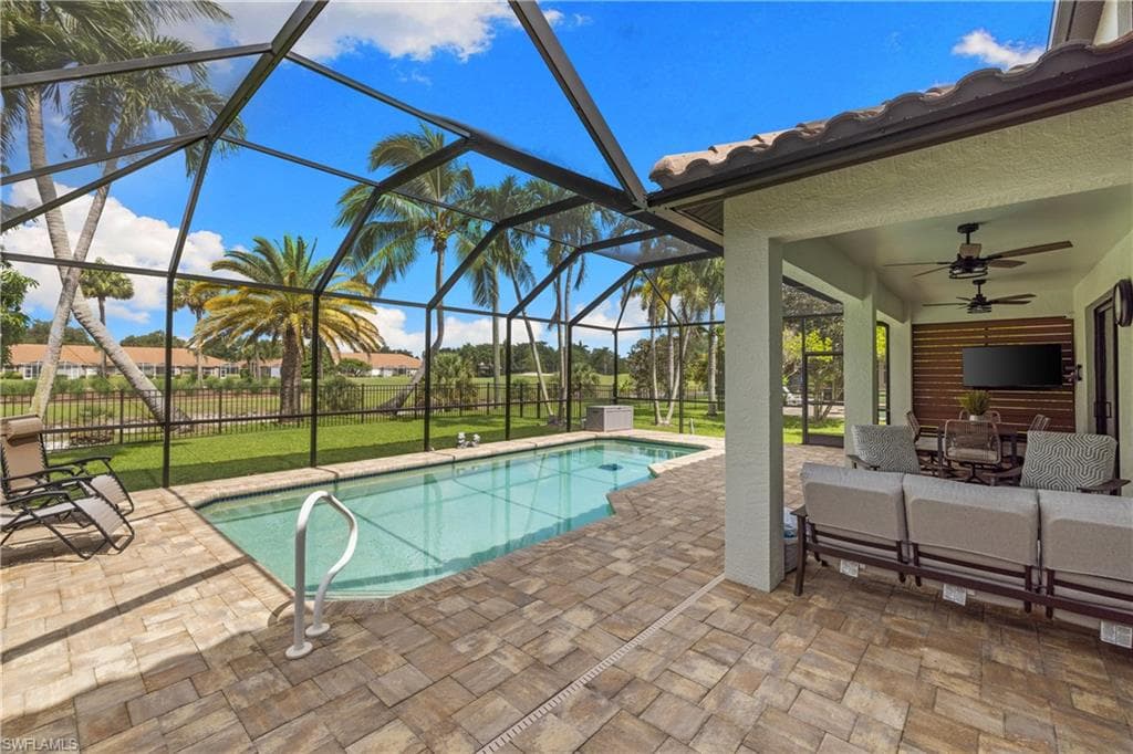 Screened lanai featuring a swimming pool with a paved deck, a covered patio with recessed lighting, and dual ceiling fans