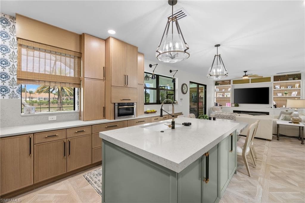 Spacious kitchen featuring light wood cabinetry, a large center island with integrated seating, and dual pendant lighting