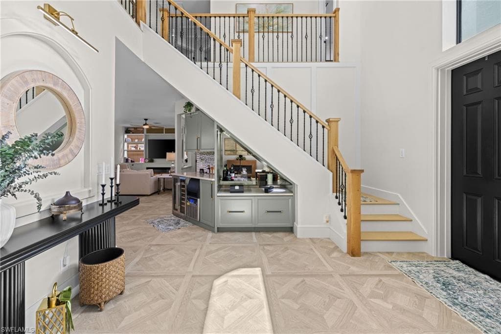 Grand entryway featuring a two-story foyer, a prominent staircase with wood handrails and wrought iron balusters, and light wood-finish flooring