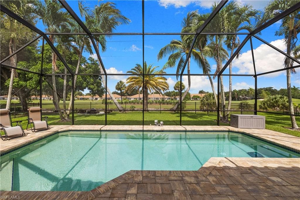 Screened outdoor pool area featuring a rectangular pool, integrated spa, and pavers