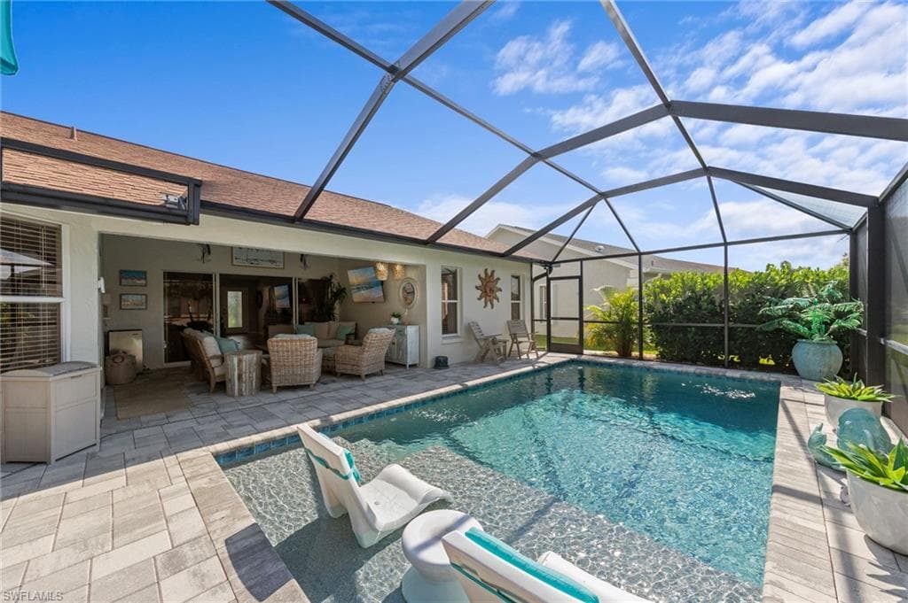 Screened-in swimming pool with an integrated sun shelf, surrounded by paver decking