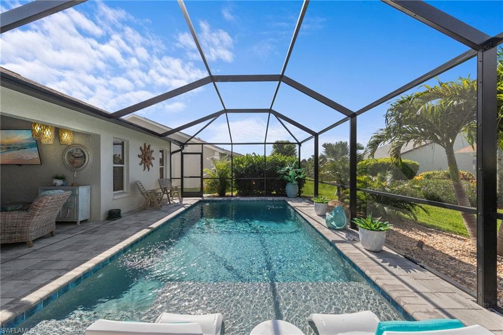 Screened-in outdoor living space featuring a saltwater swimming pool with a sun shelf