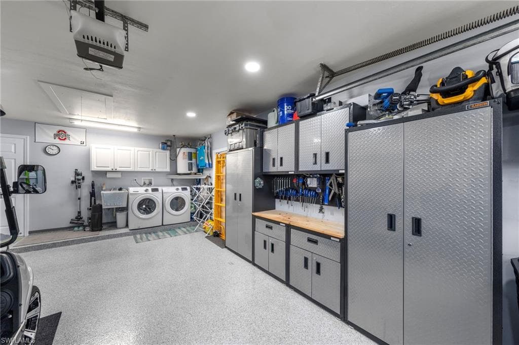Spacious garage featuring epoxy flooring, white cabinetry and a utility sink