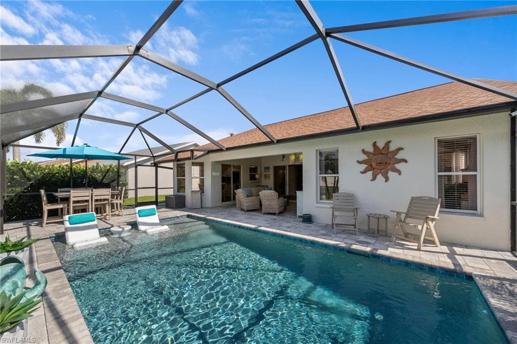 Screened outdoor living area featuring a saltwater pool with an integrated sun shelf, paver patio, and covered lanai