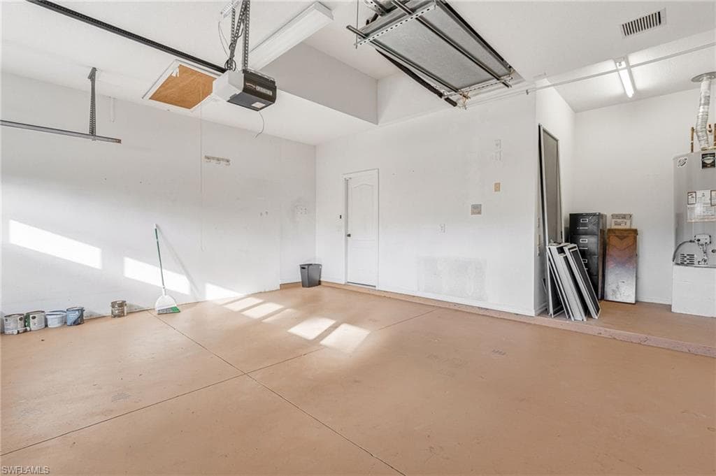 Two-car garage featuring a light-toned concrete floor, white painted walls, and an automatic garage door opener