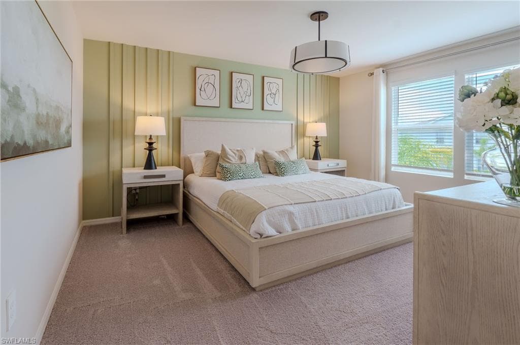 Carpeted bedroom featuring a decorative accent wall, a drum pendant light fixture, and large windows with blinds