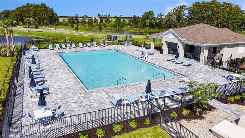 Expansive community pool with a surrounding paver deck, a covered lounge area, and direct access to a clubhouse