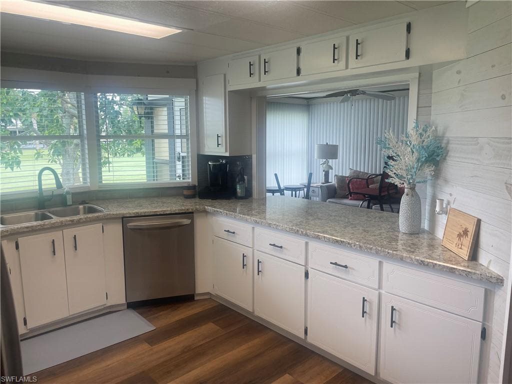 Kitchen featuring white cabinetry with dark hardware, speckled countertops, and a double basin sink with a gooseneck faucet