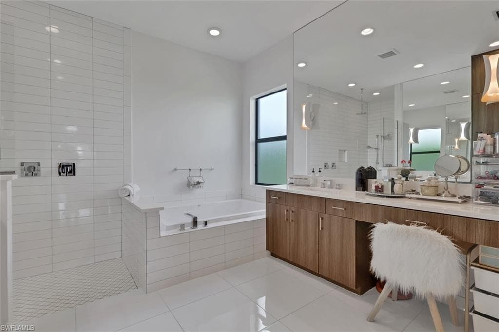 Dual vanities with ample storage space, custom lighting, spacious soaking tub, and a large, updated shower.