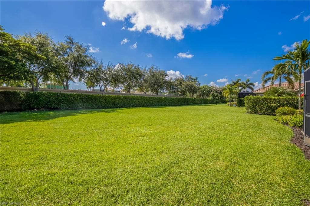 Expansive green lawn with mature landscaping and privacy hedges