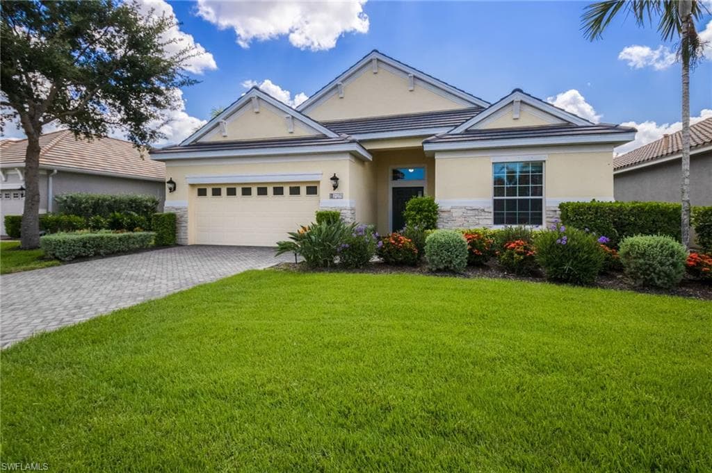 Single-story residence featuring a stucco exterior with stone accents, a paver driveway, a two-car garage, and established landscaping