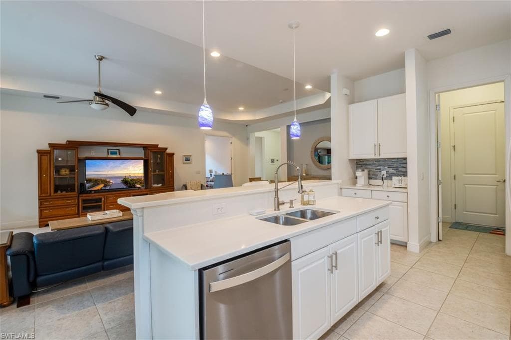 Kitchen island with a double basin stainless steel sink, stainless steel dishwasher, and white cabinetry
