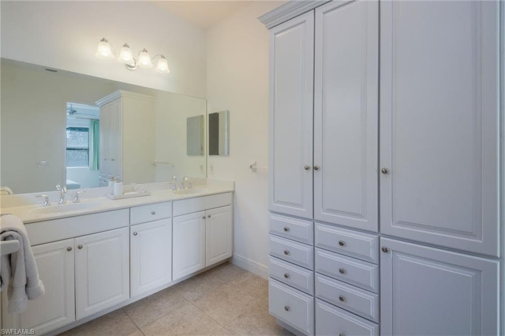Dual vanity featuring white cabinetry, integrated sinks, a full-width mirror, and chrome fixtures