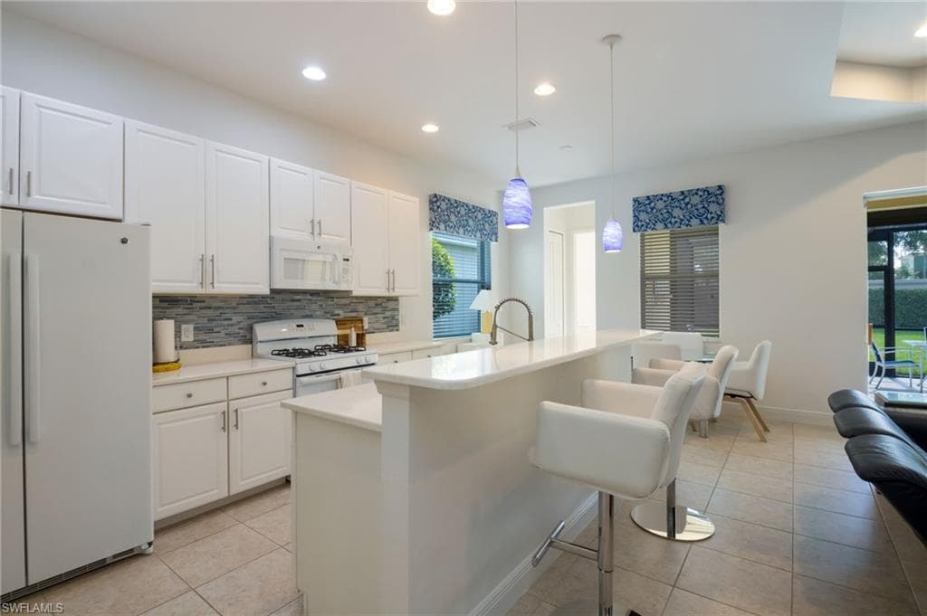 Modern kitchen featuring white cabinetry, a tiled backsplash, and recessed lighting
