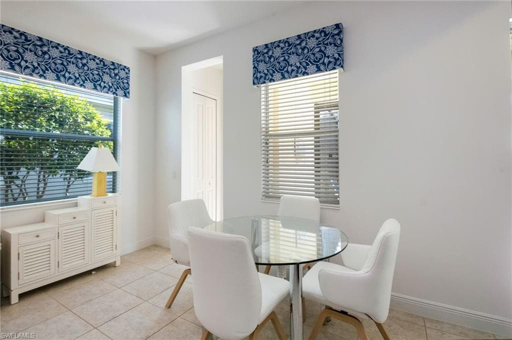 Bright room featuring two windows with white blinds and blue valances, light-colored tile flooring, and white walls