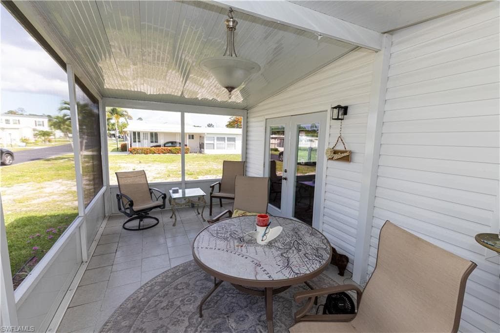 Screened outdoor living area featuring tiled flooring, a textured ceiling, and a central ceiling light fixture