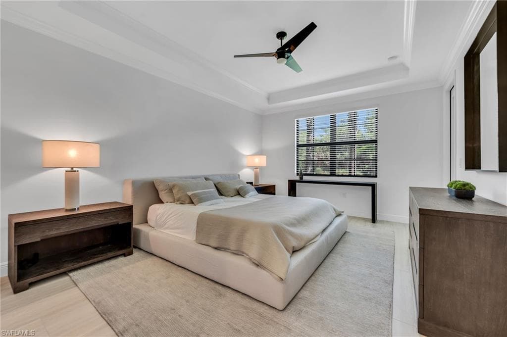Spacious room featuring a tray ceiling, crown molding, and large window with horizontal blinds
